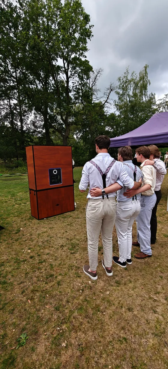 De houten photobooth in het gras met gasten ervoor