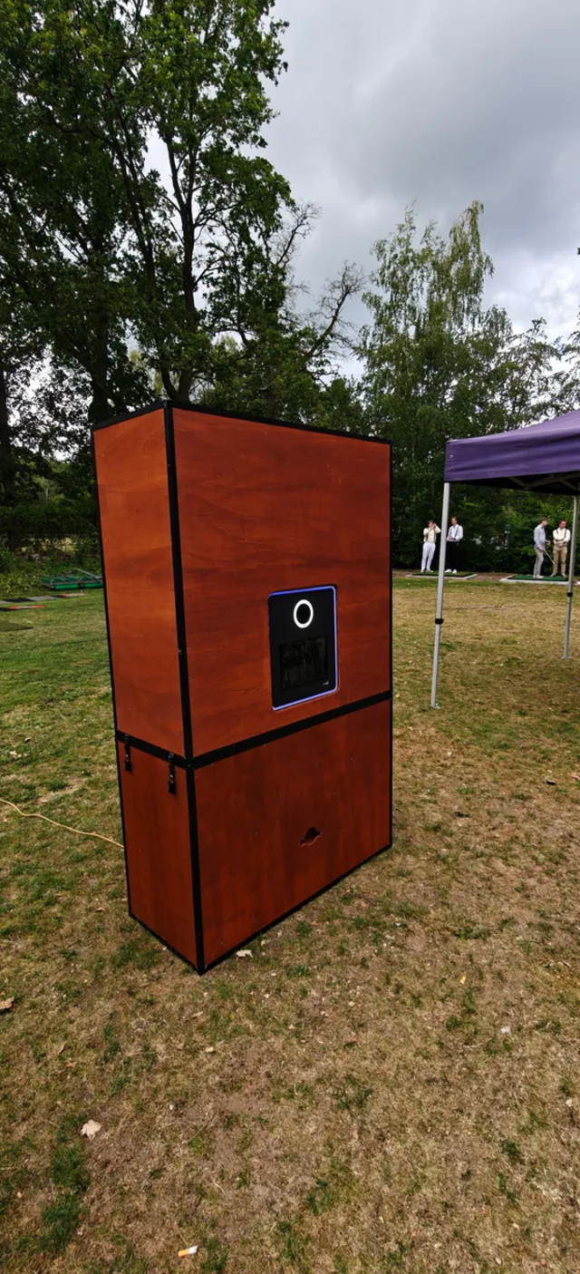 De photobooth in een houten kast, buiten op een veld opgesteld
