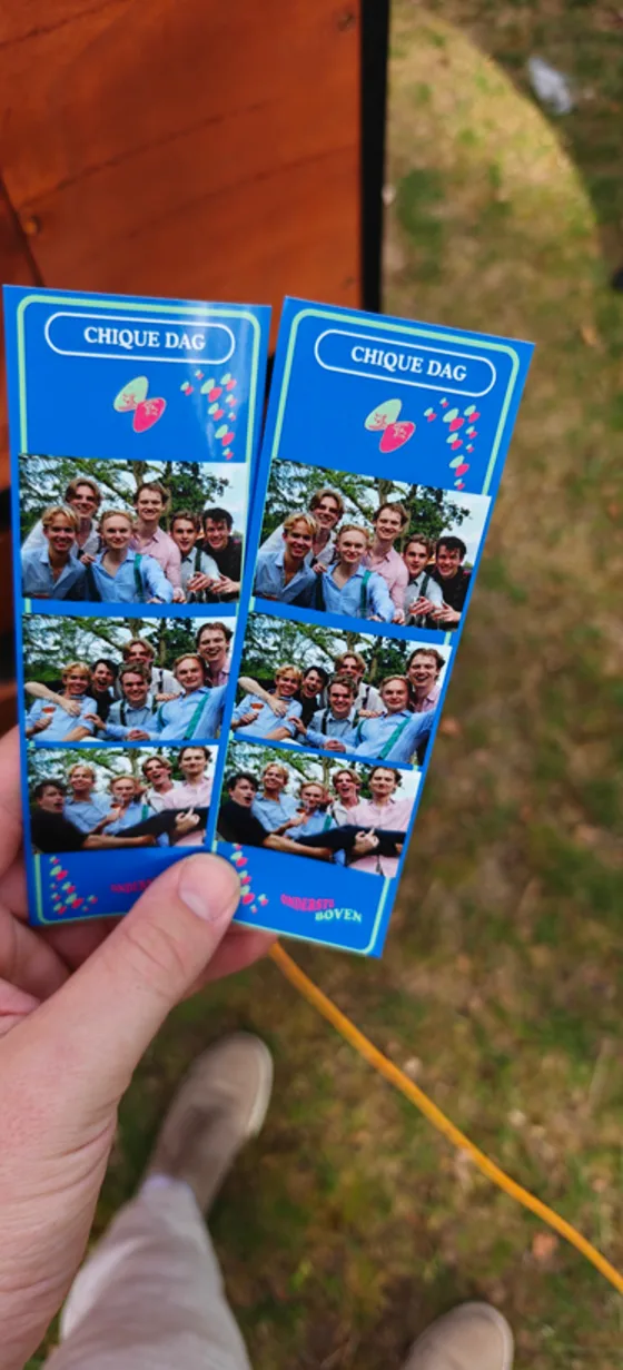 Hand met twee uitgeprinte fotostrips van een feest